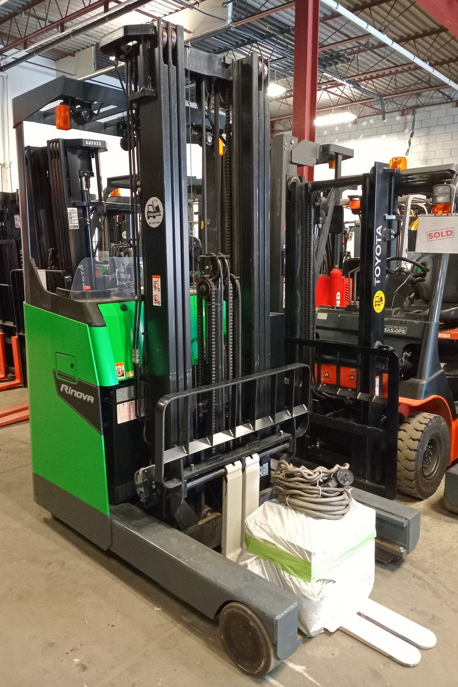 Green and gray forklift in a warehouse setting with other forklifts in the background.